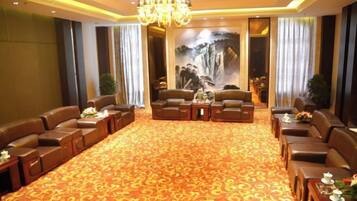 A hotel lobby with leather sofas, a carpeted floor, a chandelier, and a mural.