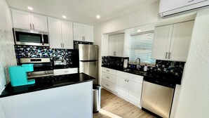 A modern kitchen with white cabinets, a black countertop, and stainless steel appliances. - Charming Longboat Key Bungalow minutes from beaches, restaurants, parks (Longboat Key)