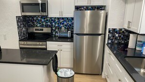A modern kitchen with white cabinets, stainless steel appliances, a microwave, a toaster, and a refrigerator. - Charming Longboat Key Bungalow minutes from beaches, restaurants, parks (Longboat Key)