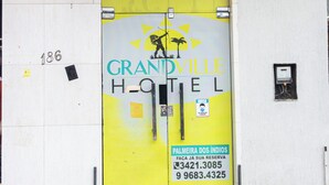 La entrada principal del Hotel Grandville, con una puerta amarilla y un cartel que indica el nombre y la información de contacto del hotel.