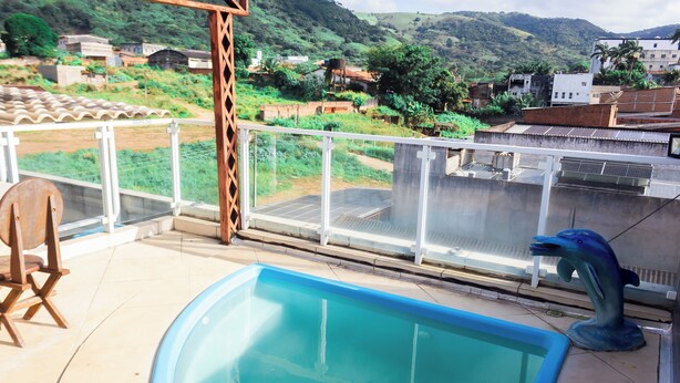 Una piscina con vista a una colina y edificios al fondo.
