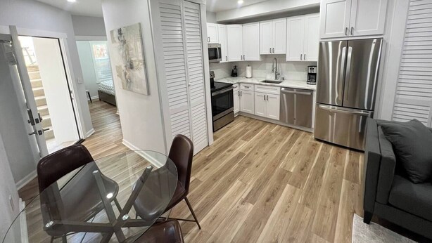 A modern kitchen with white cabinets, stainless steel appliances, and a glass dining table.