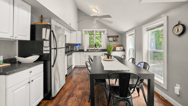 A kitchen with white cabinets, a black refrigerator, a dining table with chairs, and a ceiling fan. - Charming 2-bedroom farmhouse with WiFi and AC in fabulous Bloomington (Bloomington)