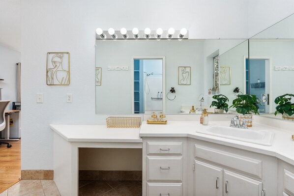 A modern bathroom with a large mirror, vanity, and a shower area.