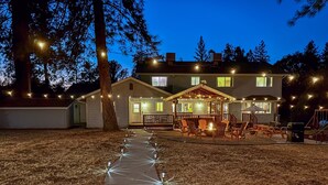 A house with a covered porch, a fire pit, and string lights. - Pool*Sauna*HotTub*Theater*Bar*Pickleball*Volleyball (Oakhurst)