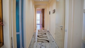 Un couloir avec un tapis à motifs, un plancher en bois et une porte sur le côté droit.
