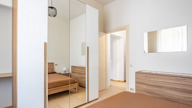 Una camera da letto con un letto, uno specchio e un armadio con ante scorrevoli.