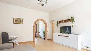 Un soggiorno moderno con divano, tavolo da pranzo, televisione e angolo cottura.
