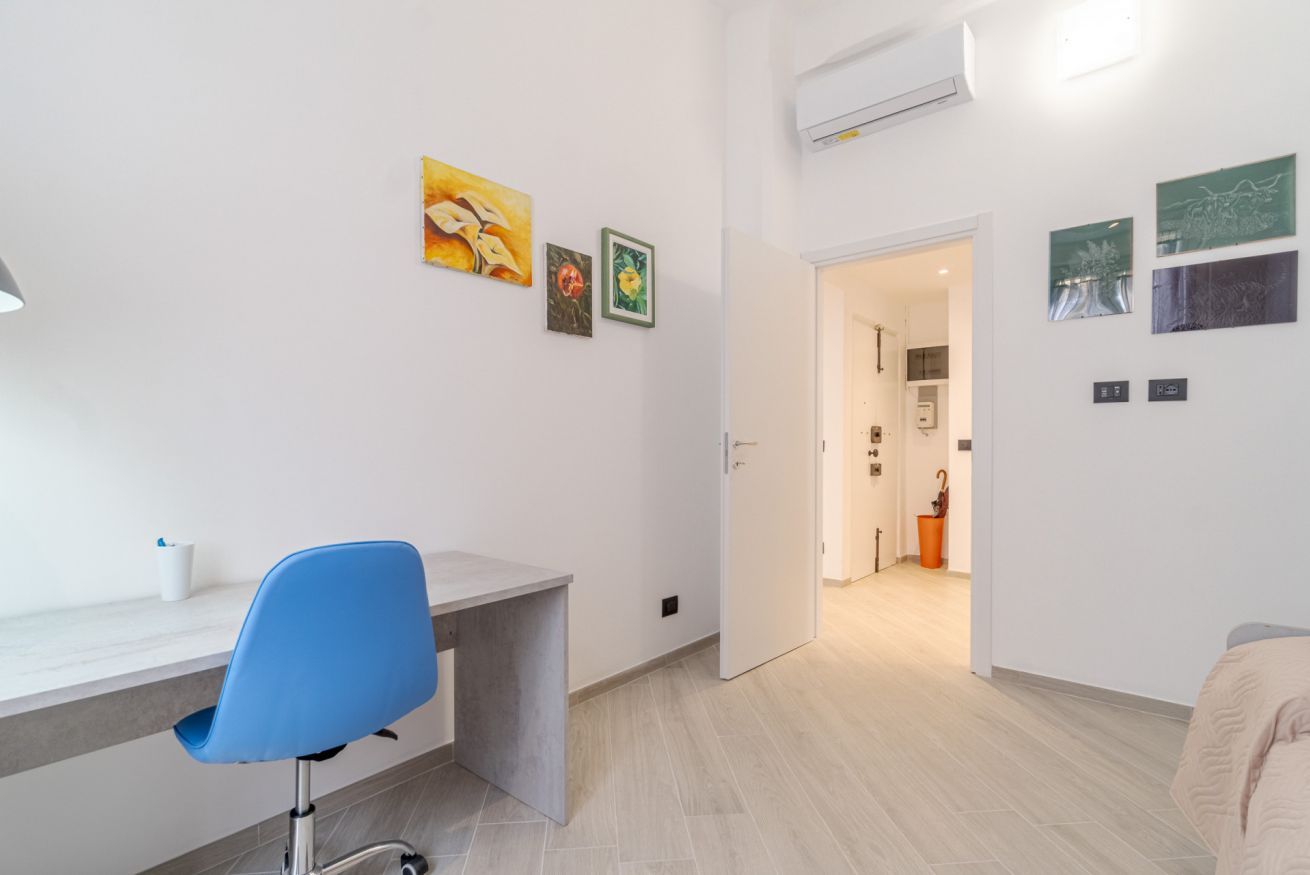 Quarto moderno com escrivaninha, cadeira e obras de arte nas paredes.