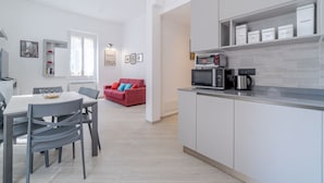 Une cuisine moderne avec un coin repas, un canapé rouge et une machine à café.