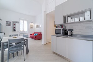 A modern kitchen with a dining area, a red sofa, and a coffee machine.