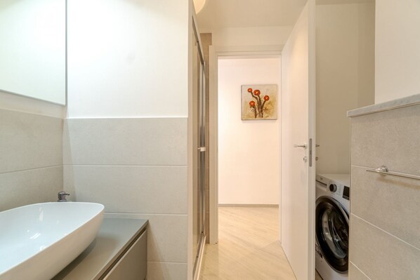 Une salle de bain moderne avec un grand lavabo, une douche et un lave-linge.
