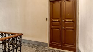 Une porte en bois fermée, dotée d’une poignée en métal, d’une rambarde en métal et d’un sol texturé.