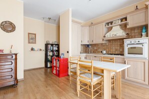 Une cuisine avec des meubles de rangement en bois, une cuisinière blanche et une table à manger avec des chaises.