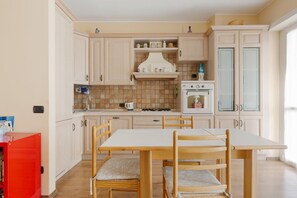 A kitchen with white cabinets, a tiled backsplash, a stove, and a dining table with chairs.