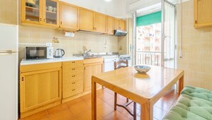 Una cocina con armarios de madera, microondas, estufa y una mesa de comedor con un tazón.