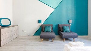 A modern room with two grey armchairs, a wooden sideboard, and a teal accent wall. - GuestHost - Turquoise Mini Flat x2 near Centrale FS (Milan)