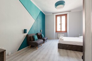 A modern bedroom with a bed, a sofa, and a window.