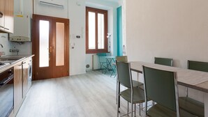 A kitchen with a stove, sink, and window. There is a dining table with chairs. - GuestHost - Turquoise Mini Flat x2 near Centrale FS (Milan)