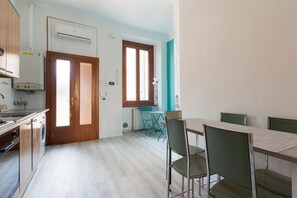 Une cuisine équipée d’une cuisinière, d’un évier et d’une fenêtre. On y trouve également une table à manger avec des chaises.