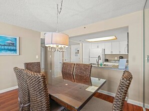 A dining area with a table and chairs, a hanging light fixture, and a view into the kitchen area. - 2BR/2BA Oceanview Condo at Kingston Resort (Myrtle Beach)