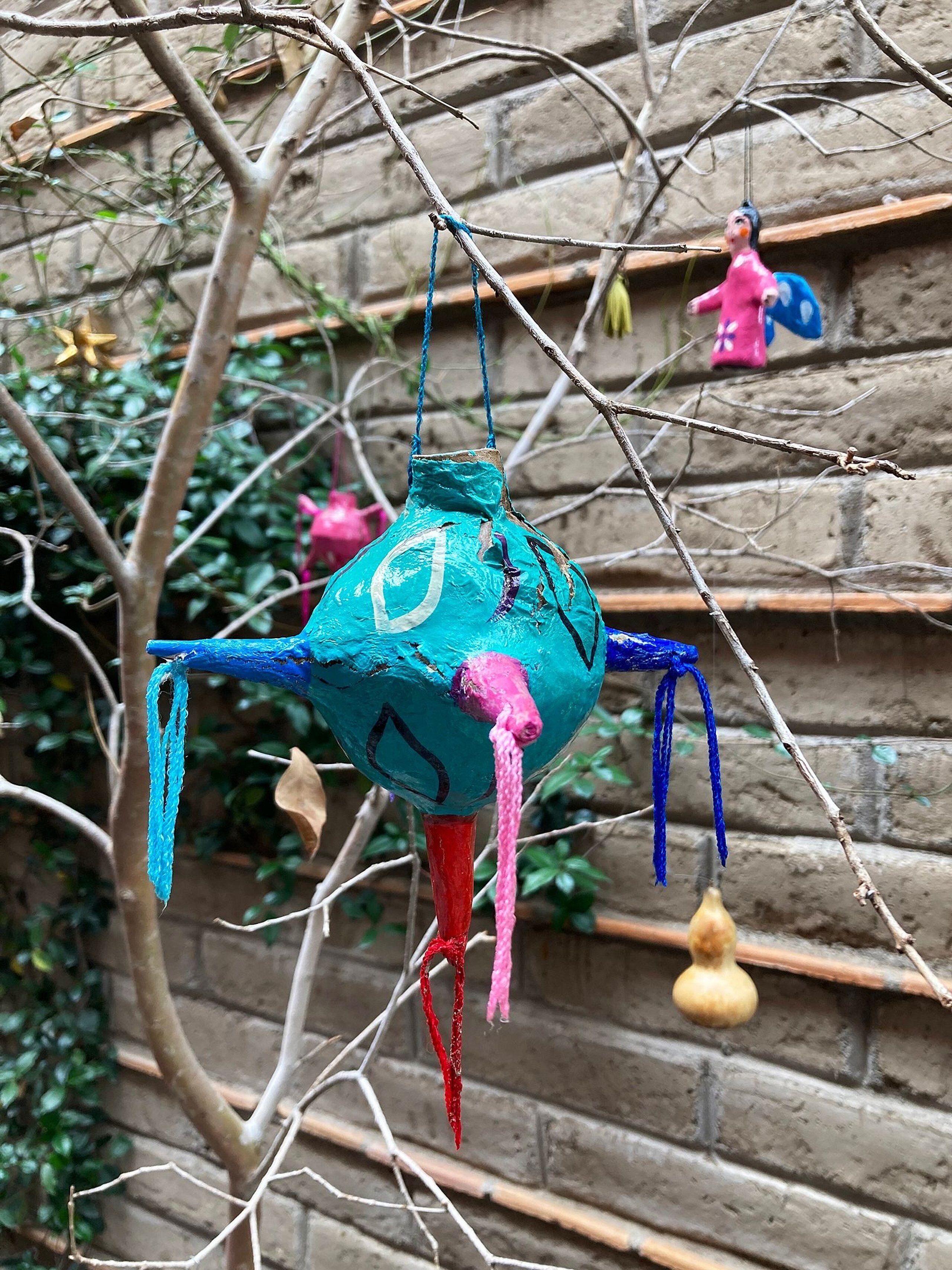 A hanging decoration with a blue and pink color scheme, attached to a branch.