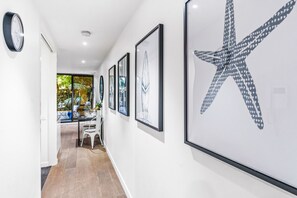 A hallway with framed artwork on the walls, a dining area with a table and chairs, and a large starfish decoration.