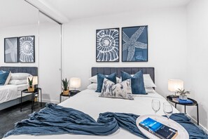 A modern hotel room with a large bed, two bedside tables, and artwork on the walls.
