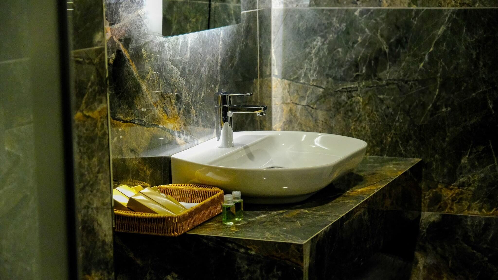 Un baño con un lavamanos blanco grande y ovalado, un grifo moderno y un box de ducha de cristal.