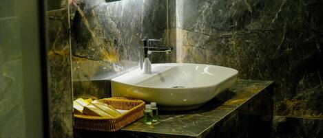 Un baño con un lavamanos blanco grande y ovalado, un grifo moderno y un box de ducha de cristal.