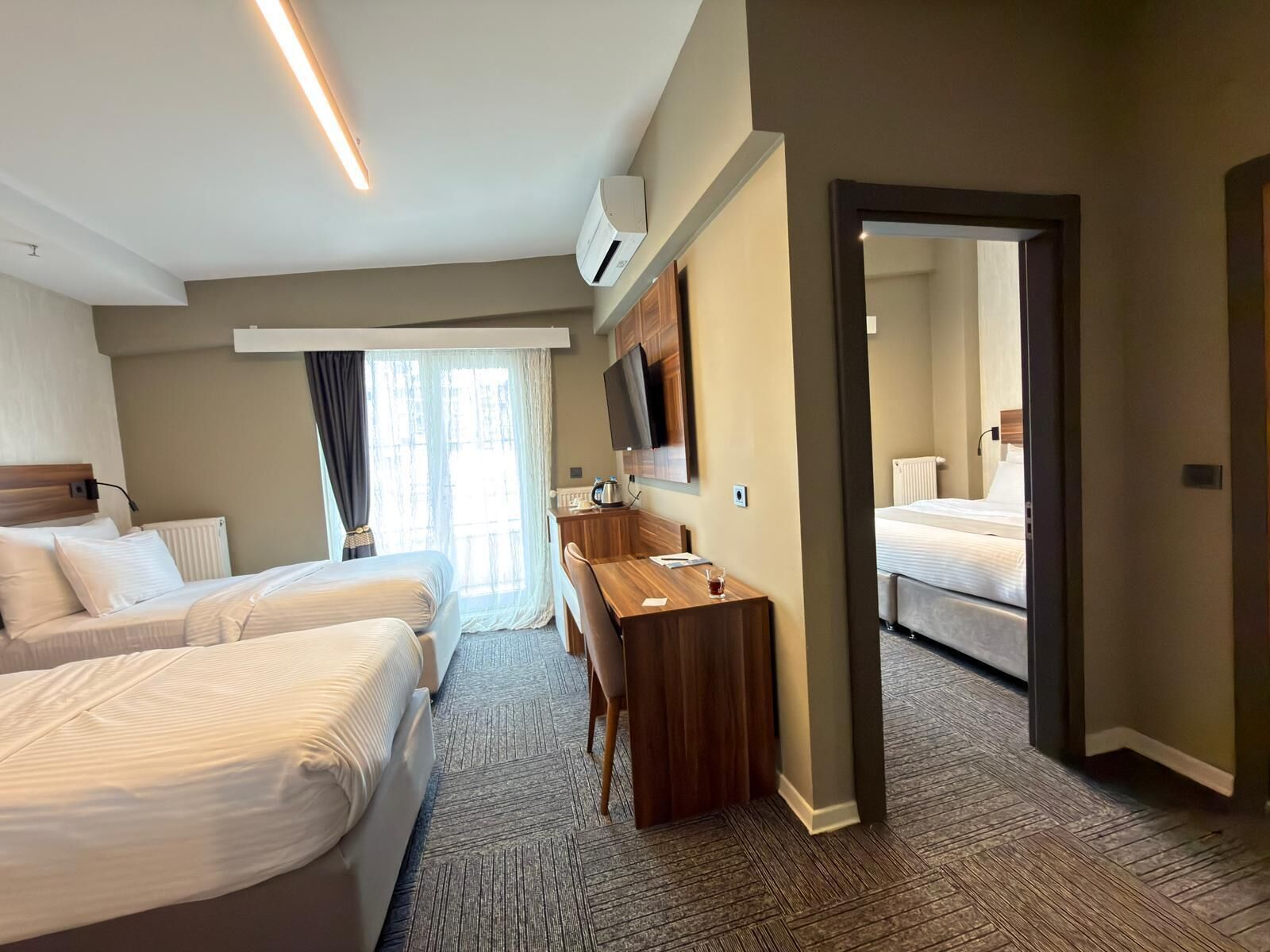 Una habitación de hotel con dos camas, un escritorio, un televisor y un espejo grande.