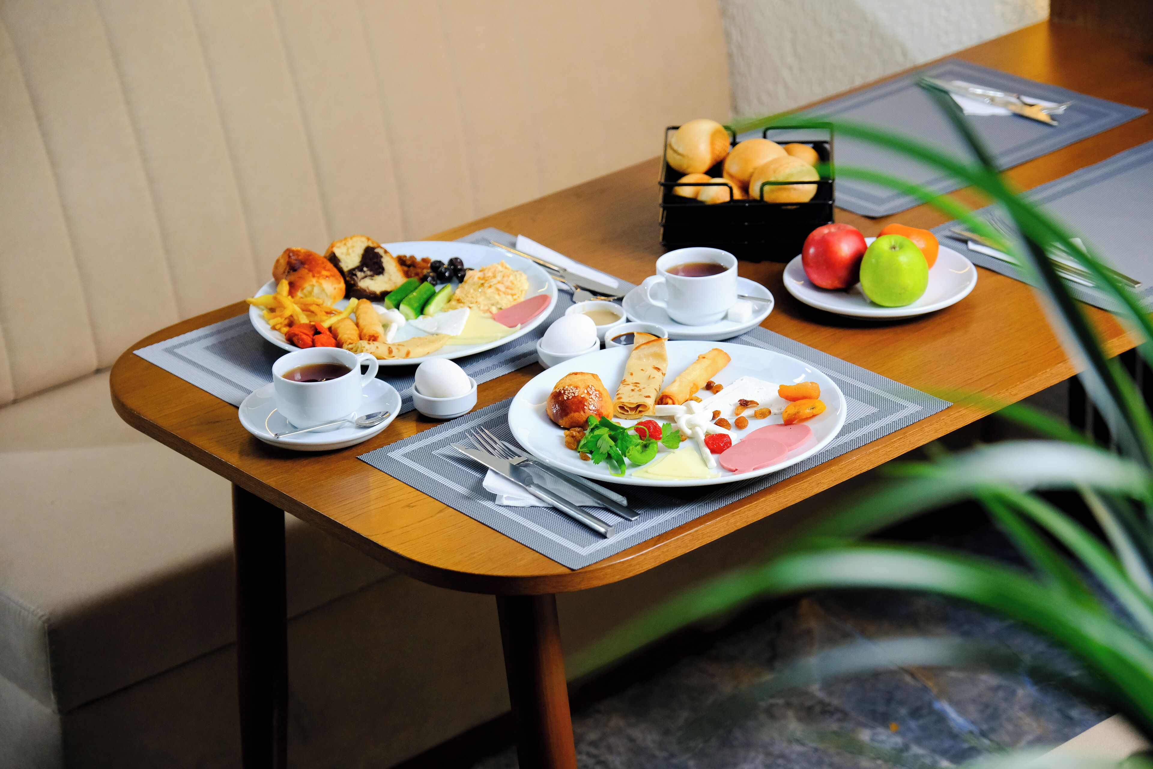 Een eettafel met borden eten, een broodmand en een kop koffie.