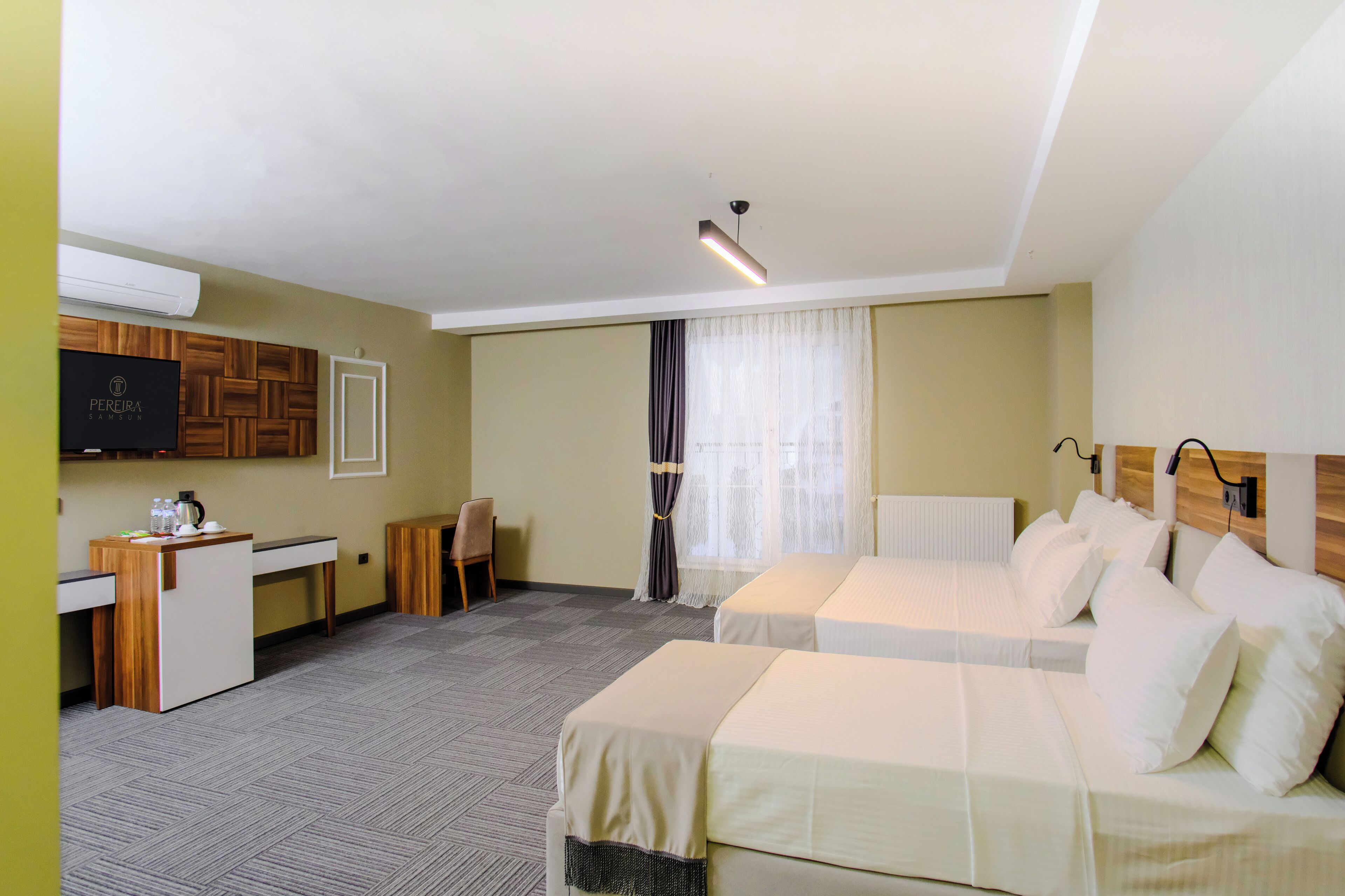 Habitación de hotel con dos camas, un escritorio, una silla, un televisor y una ventana con cortinas.