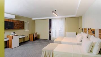 Habitación de hotel con dos camas, un escritorio, una silla, un televisor y una ventana con cortinas.