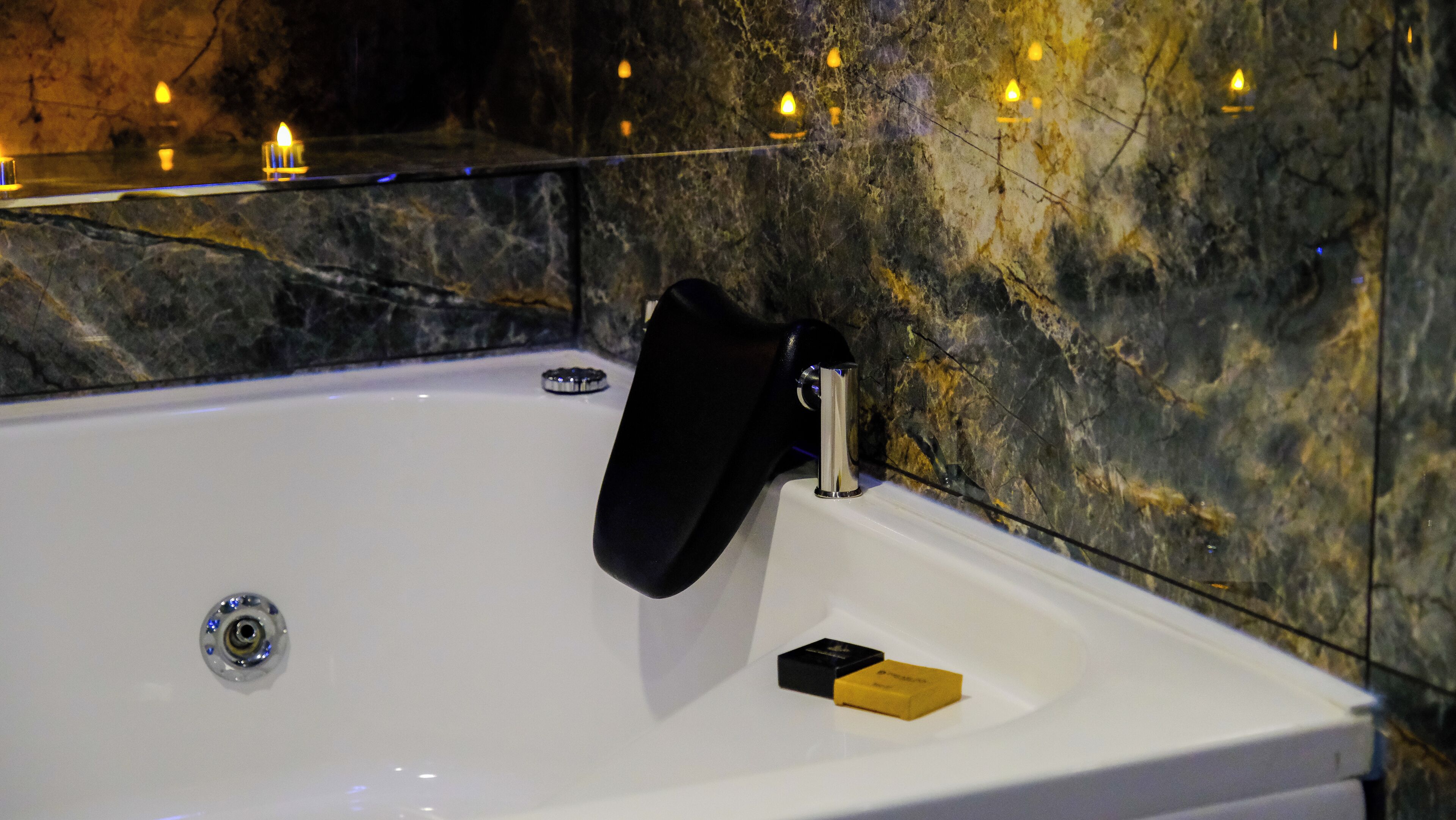 A white bathtub with a black faucet, a soap bar, and a small black container.