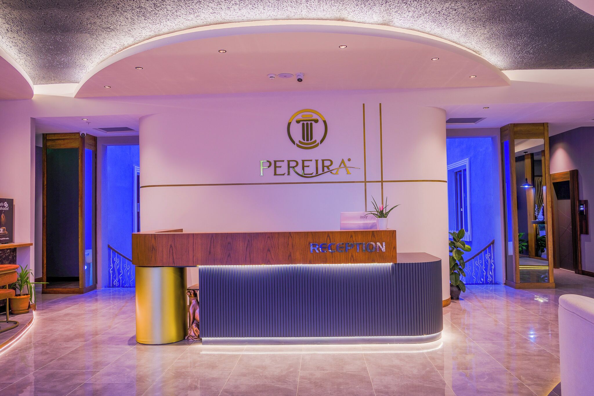 A reception area with a modern design, featuring a wooden reception desk, a logo above it, and a blue-lit wall.