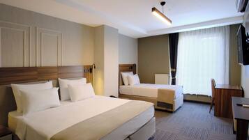 A hotel room with a large bed, a smaller bed, a desk, and a TV.