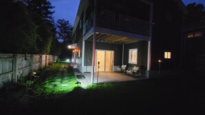 A modern house with a covered patio, a visible door, and a small garden area.