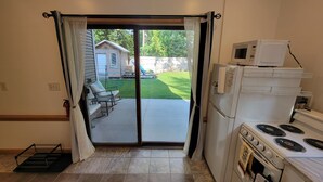 A kitchen with a stove, microwave, and refrigerator. There is a sliding glass door leading to a patio with outdoor furniture.