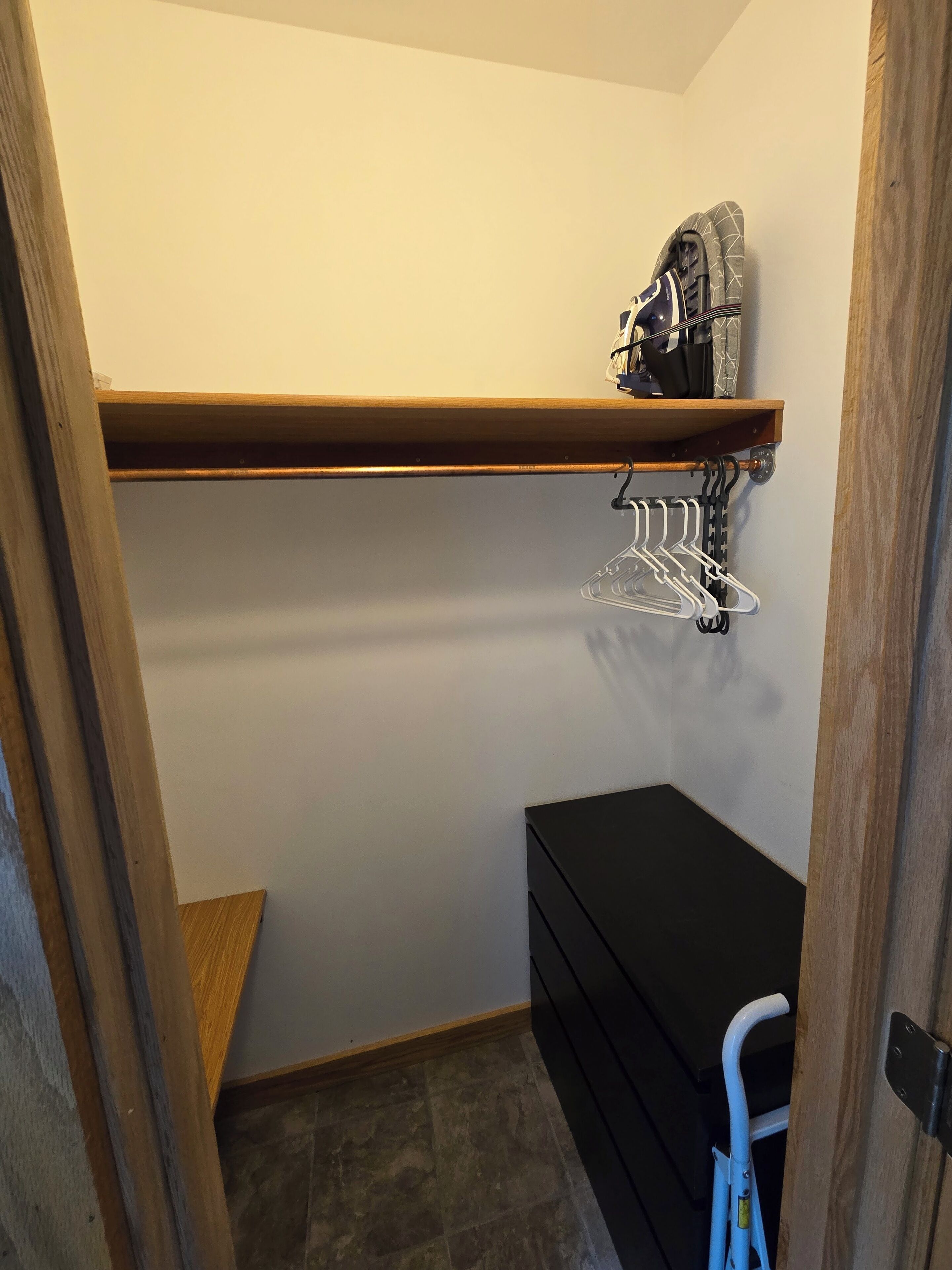 Ein Schrank mit einer Holzwand, einem schwarzen Stauraum und einem blauen Klappstuhl.