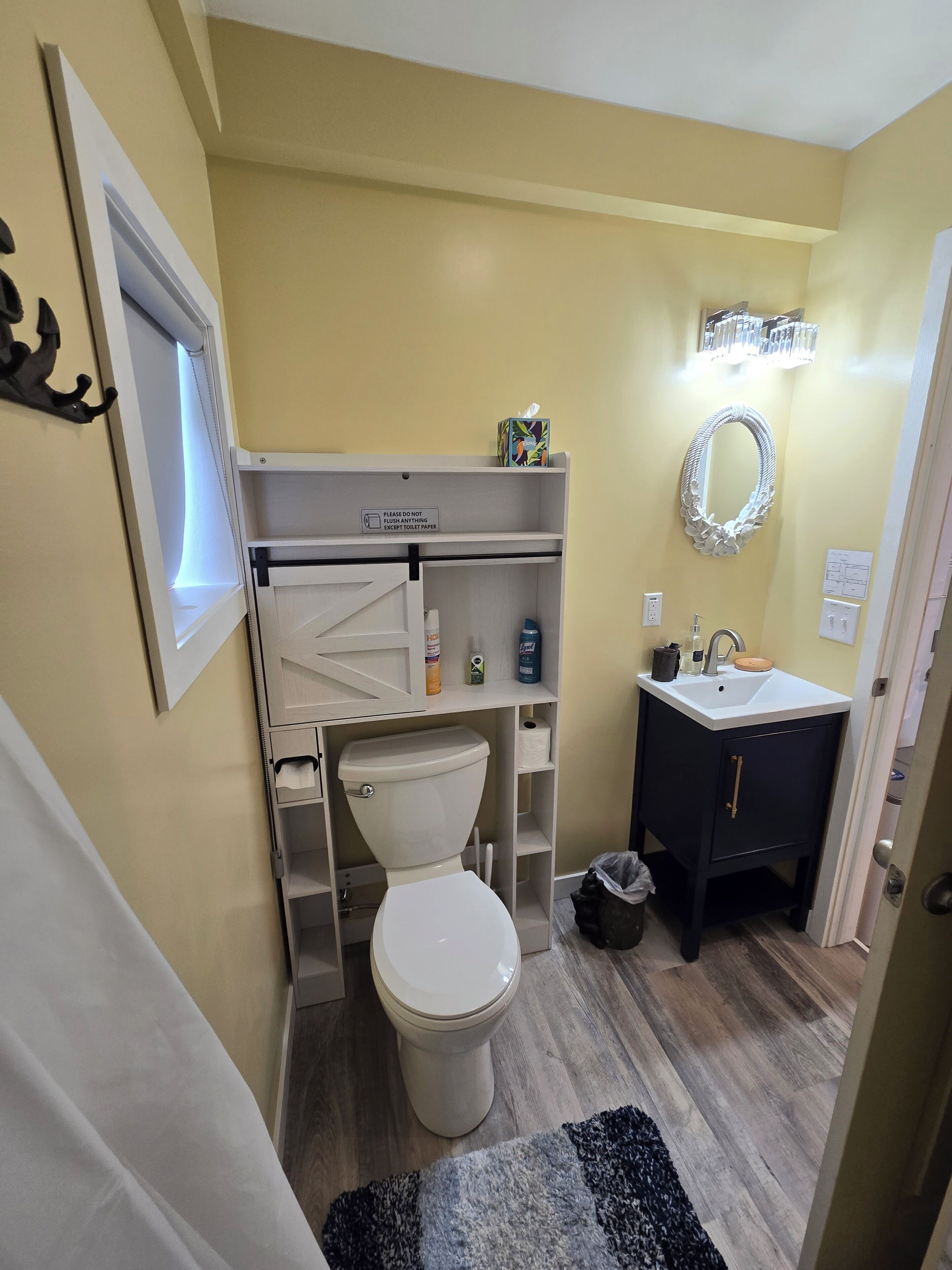 Een kleine badkamer met toilet, wastafel en opbergplanken.