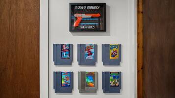 A wall with a framed emergency instruction sign and eight retro video game cartridges.