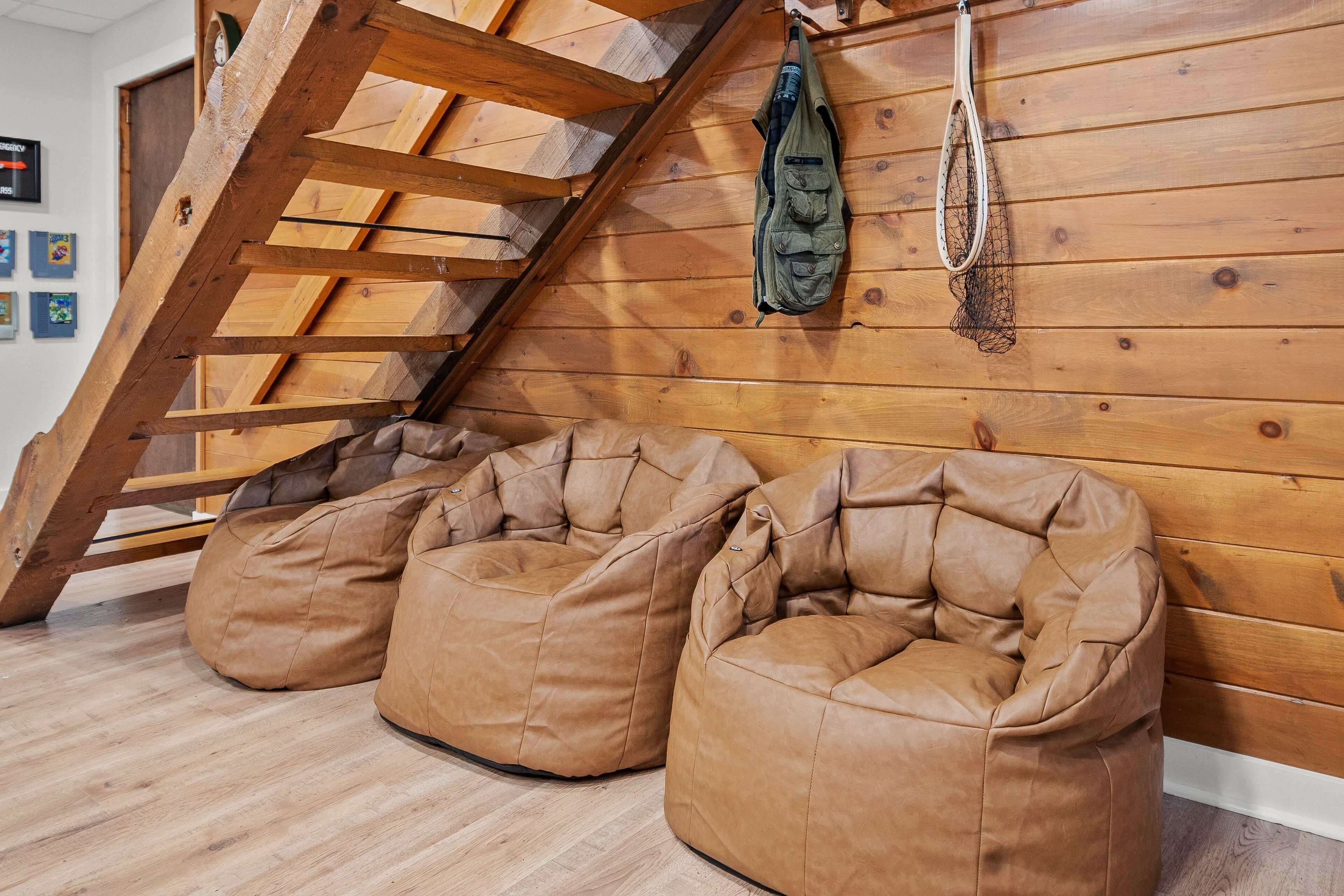 Una stanza con soffitto spiovente in legno, due sacchi di pelle marrone e una rete appesa.