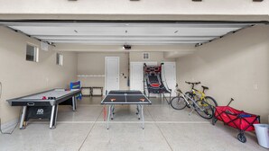 Eine Garage mit Tischtennisplatte, Basketballkorb und Fahrrädern.