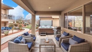 Eine Terrasse im Freien mit Korbmöbeln, einem Whirlpool und einem Grill.