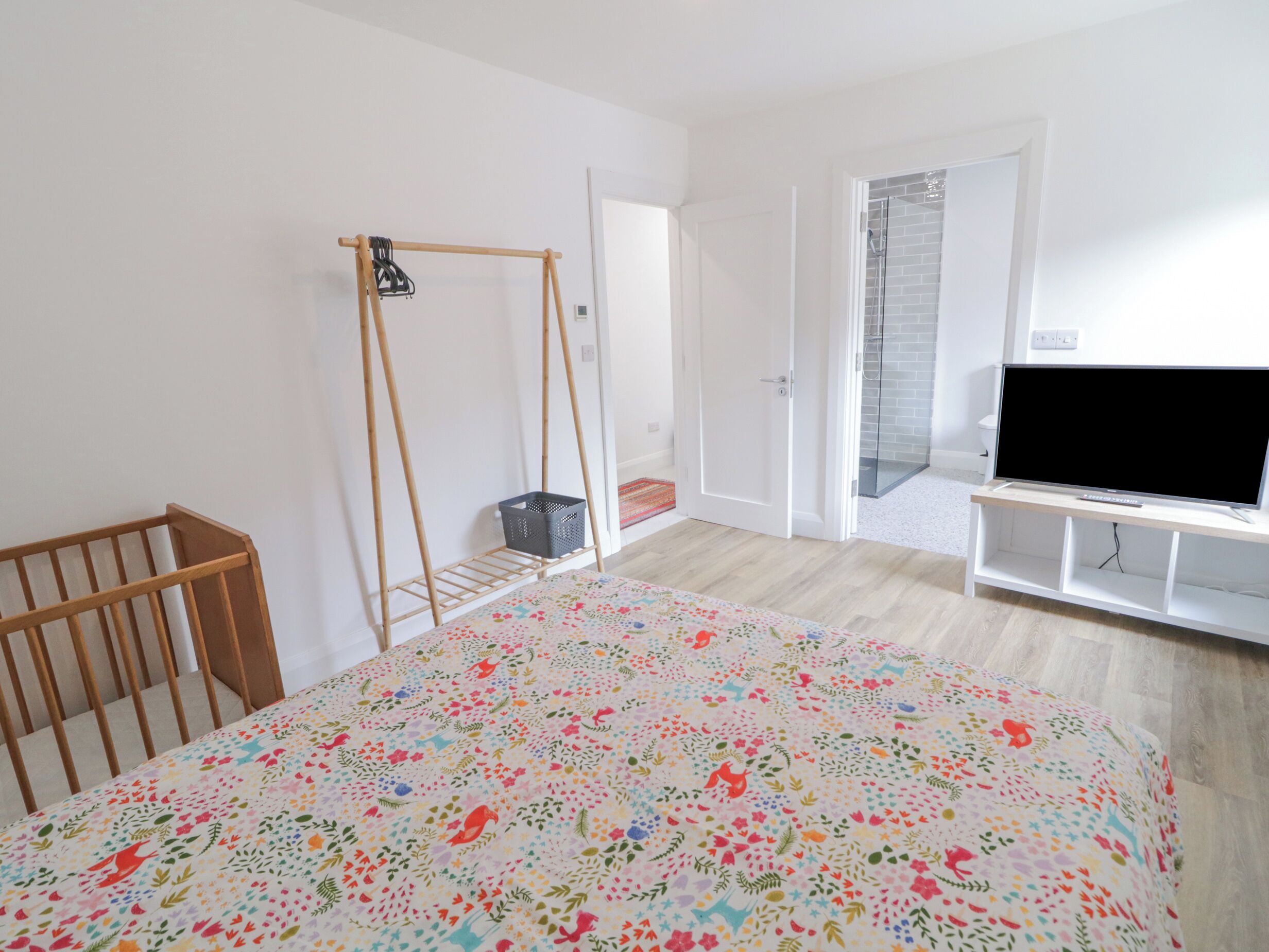 A bedroom with a bed, a TV, a wardrobe, a door, and a window.