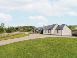 A modern house with a stone facade, a gravel driveway, and a grassy lawn.