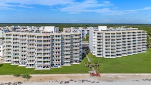 A high-rise hotel with multiple balconies, a central courtyard, and a view of the beach.