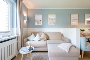 A living room with a beige sofa, a small round table, and a window with curtains.