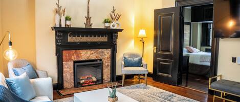 Una sala de estar con chimenea, un sofá, una mesa de centro y un sillón.